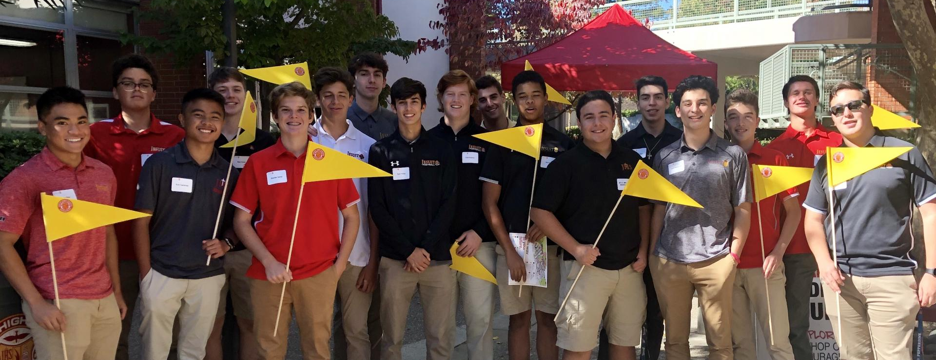 Group of student Open House tour guides with their bright yellow flags on poles.